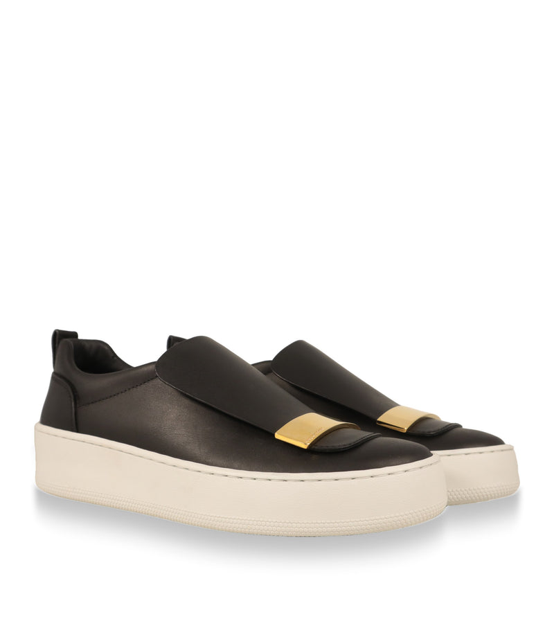 Sergio Rossi Slip-On Sneaker Paar in Schrägansicht mit goldfarbener Metallplatte auf der Lasche